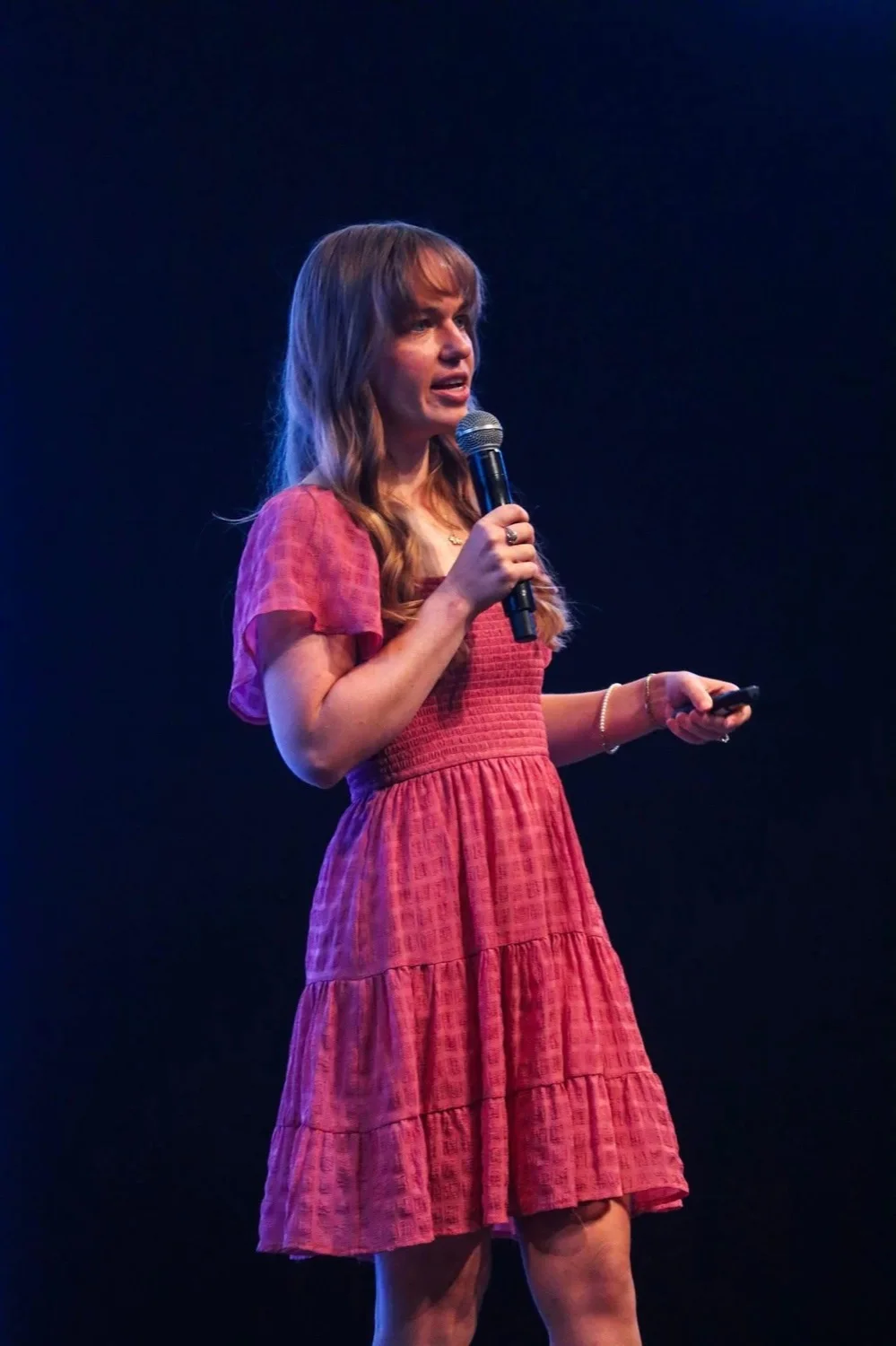 Abigail Parker speaking on stage with a microphone to a corporate audience